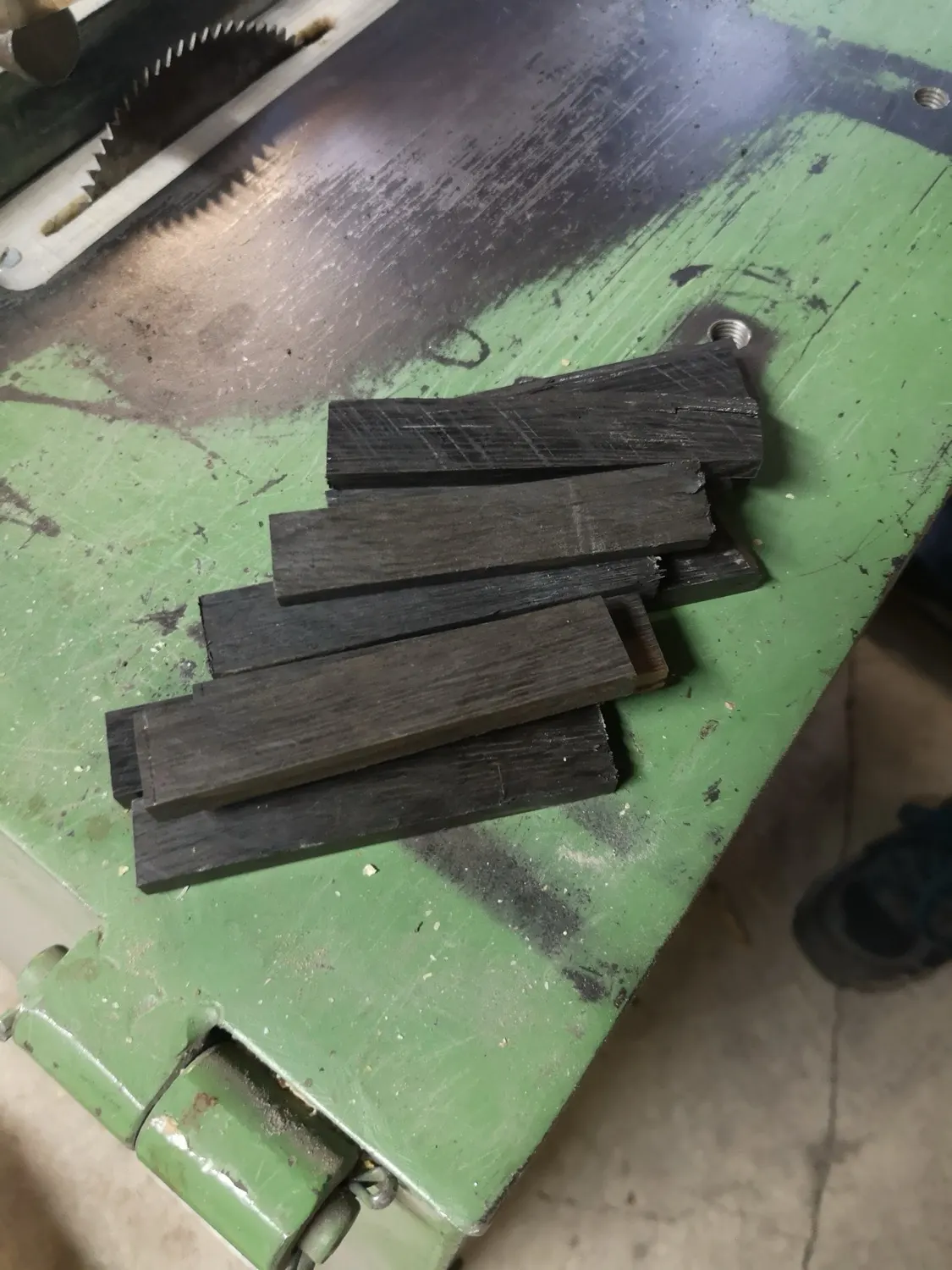 Zugeschnittene Griffschalen aus dunklem, verwittertem Holz, bereit für die nächste Reihe.
