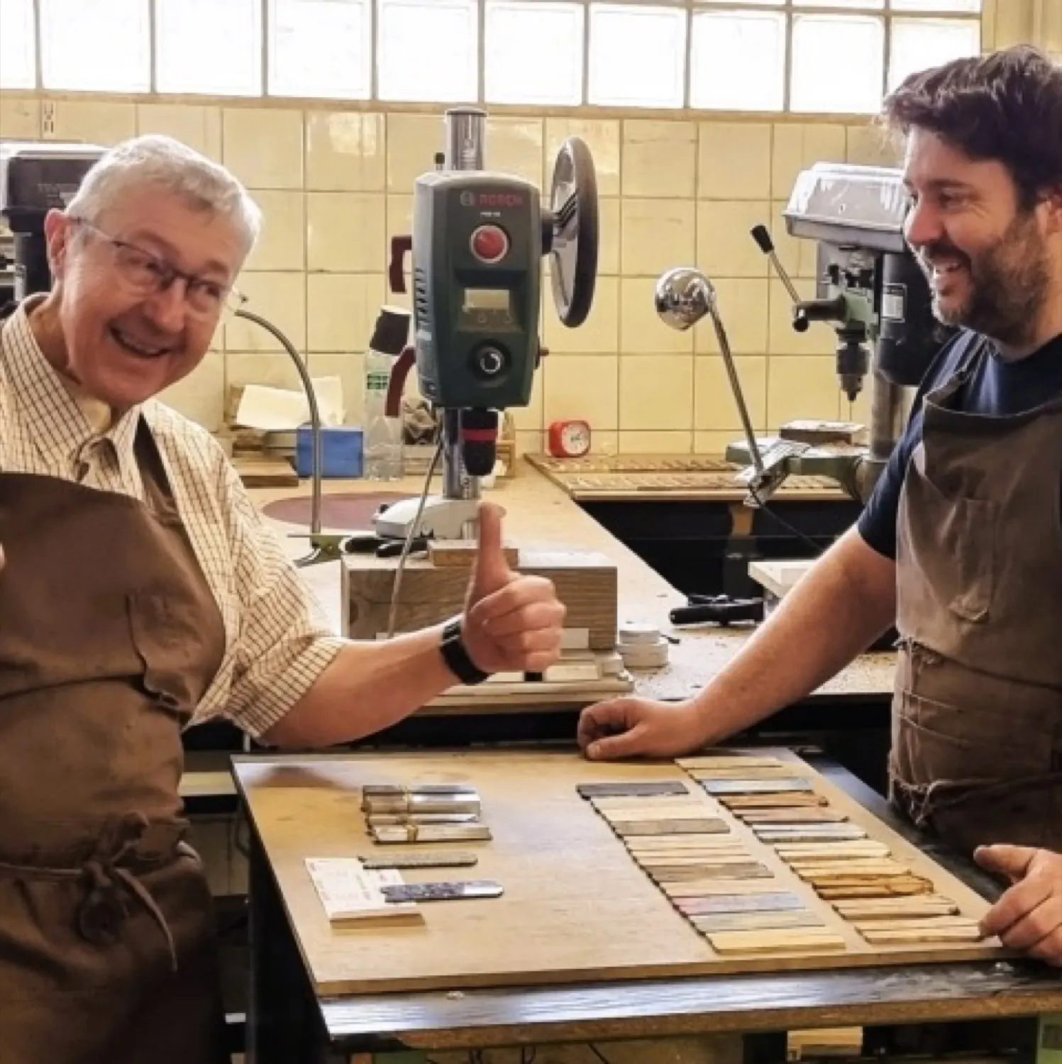 Zwei Generationen an einer Werkbank, davor die Musterbretter mit den Griffmaterialien. Nach diesen Stücken entscheidet sich, was auf ein Messer kommt.